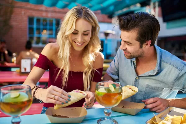 Couple at a restaurant eating tacos and drinking cocktails