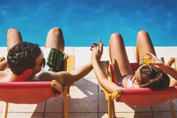 Overhead shot of a couple lounging by the pool, holding hands, and looking at each other