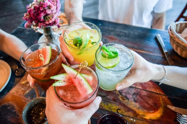 Overhead shot of four people clinking their decorative cocktails together at the center of the table